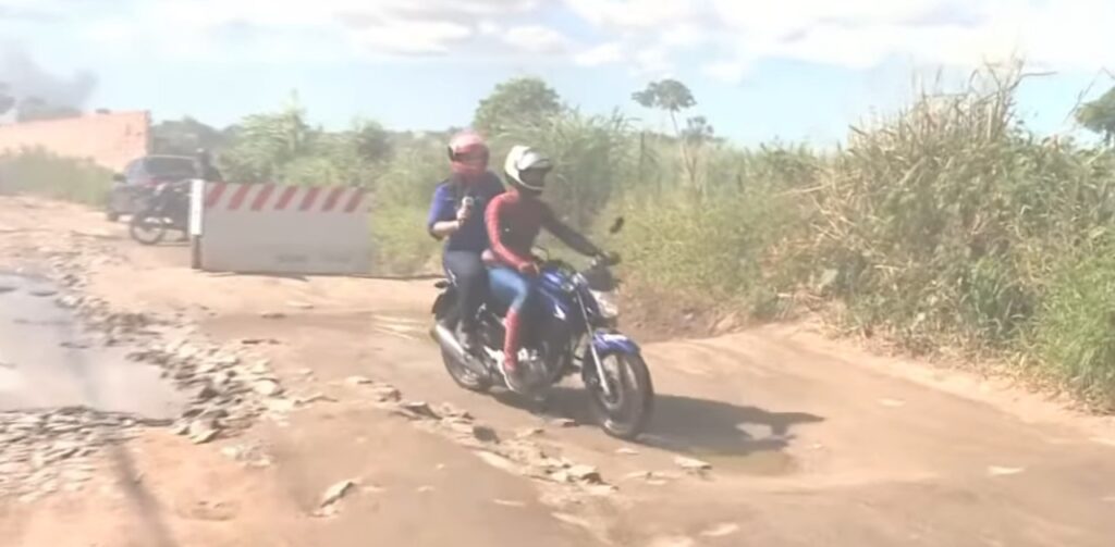 De moto, repórter se aventura em buracos de rua para mostrar situação desafiante de moradores