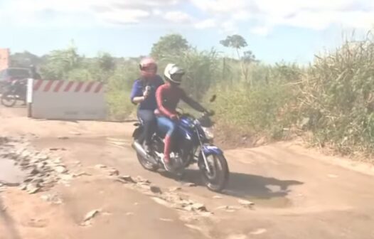 De moto, repórter se aventura em buracos de rua para mostrar situação desafiante de moradores