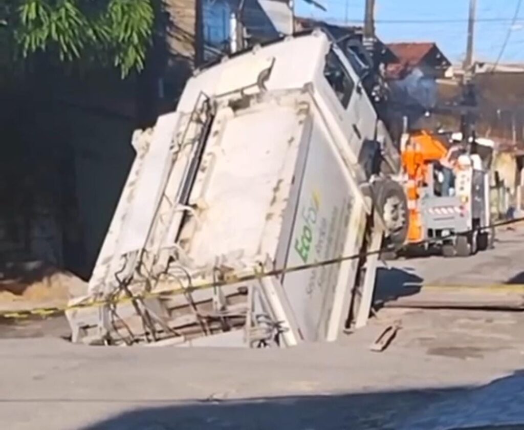 Caminhão de lixo é engolido por buraco em frente a uma creche