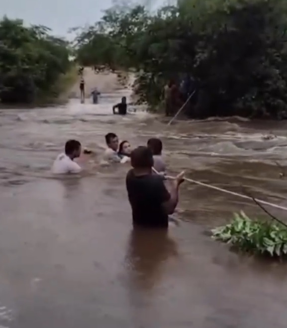 Moradores atravessam trecho inundado por enchente usando corda no Ceará