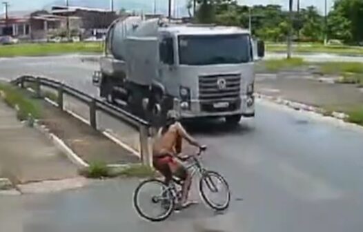 Ciclista colide em caminhão ao entrar em rotatória, cai na pista, levanta e sai pedalando